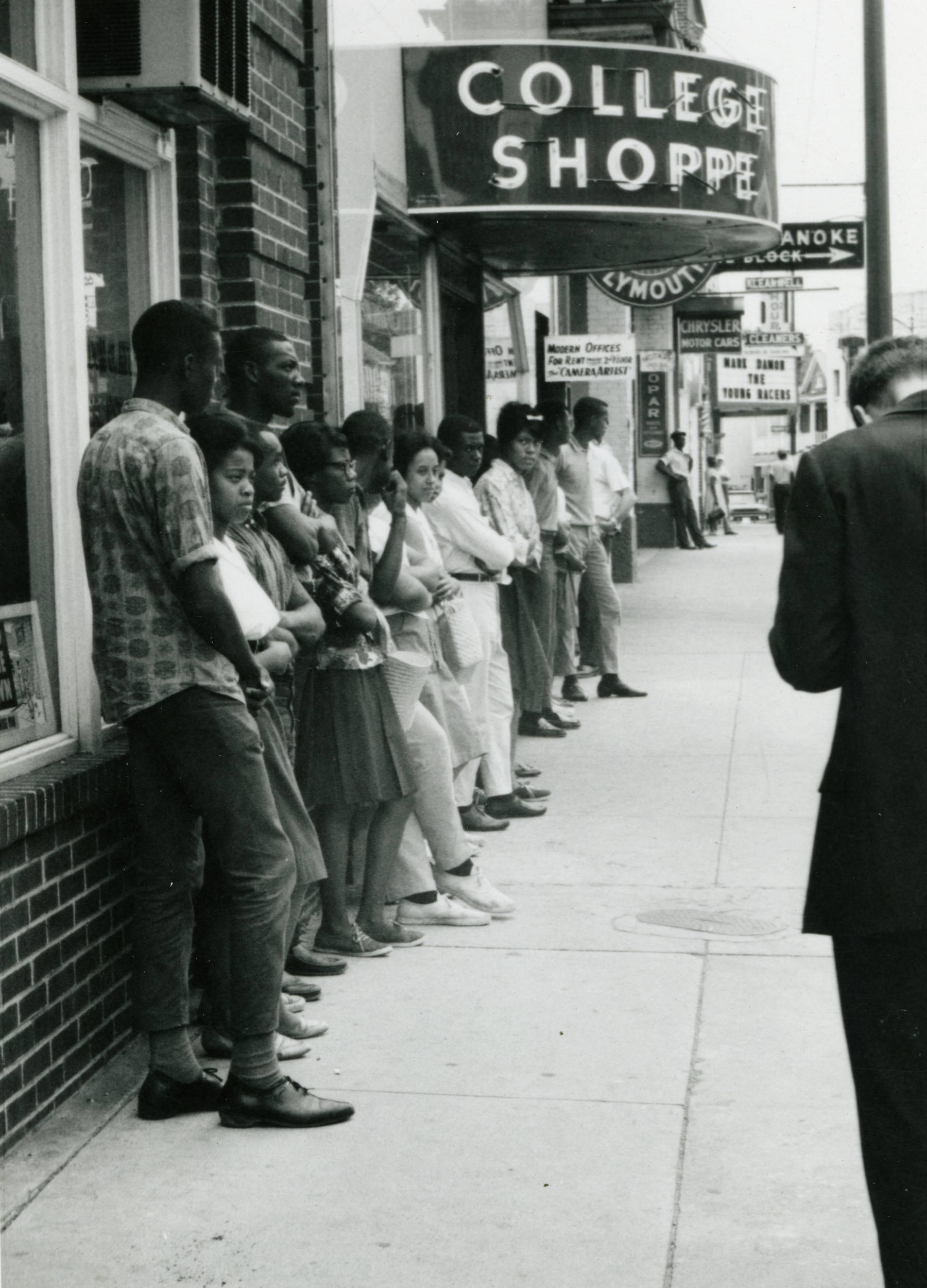 An image of peaceful demonstrators outside of the College Shoppe, standing in a single file line along the sidewalk